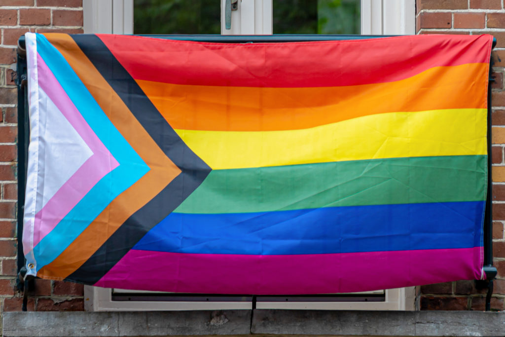 Progress pride flag (new design of rainbow flag) hanging on balcony of building, Celebration of gay pride, The symbol of lesbian, gay, bisexual and transgender, LGBTQ community in Netherlands.