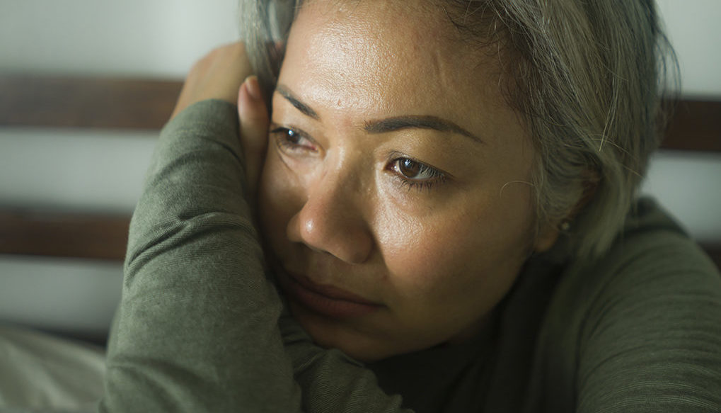 mature lady crisis - attractive middle aged woman with grey hair sad and depressed in bed feeling scared and lonely thinking worried about covid-19 virus pandemic during home lockdown