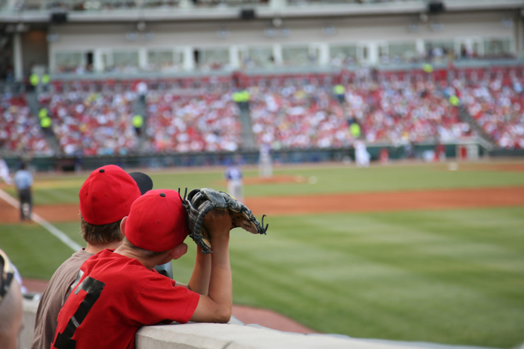 Two young boys hoping to catch a fly ball at a Cincinnati Reds baseball game