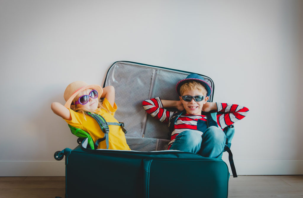 happy kids -boy and girl- enjoy packing and travel, family going on vacation