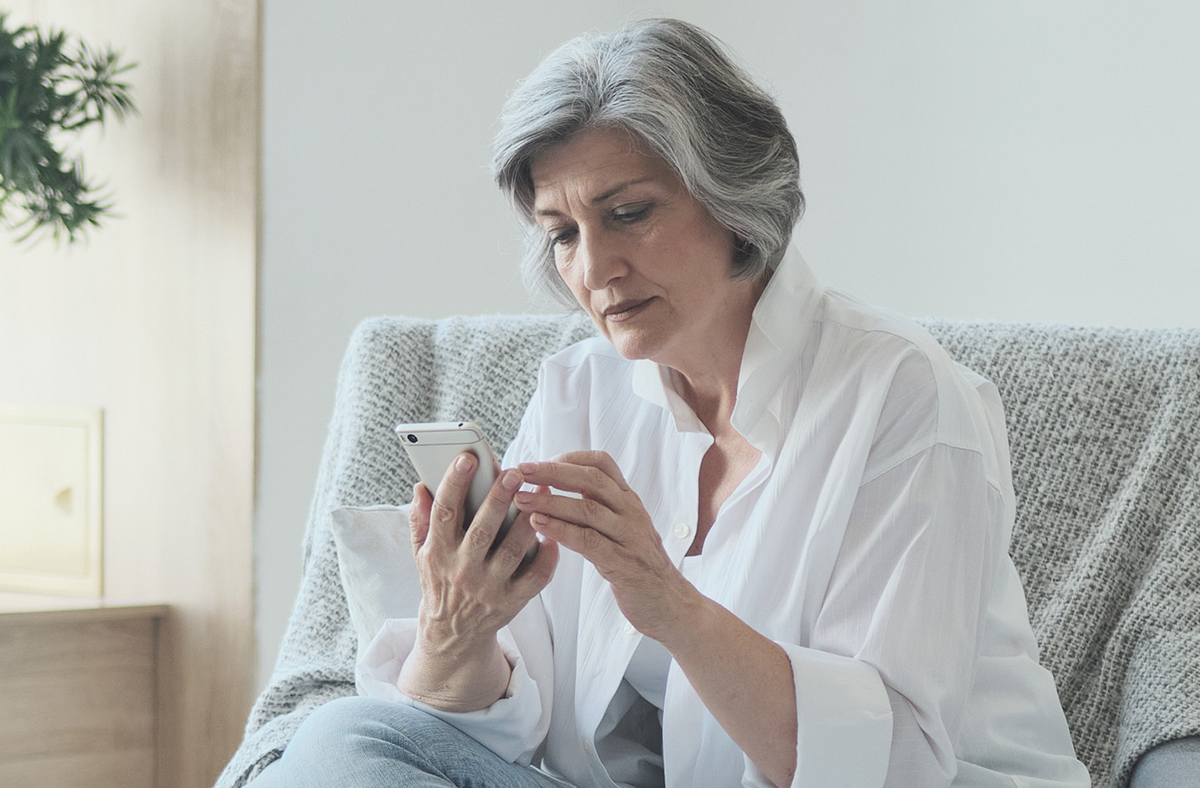 Relaxed mature old woman using mobile phone applications communicating in social network or shopping online, smartphone scrolling social media swiping scrolling, old businesswoman enjoying success