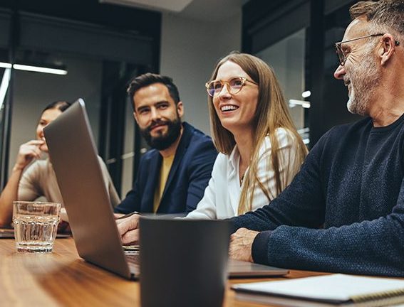 Successful group of business people having a briefing in a boardroom. Happy businesspeople smiling while working together in a modern workplace. Diverse business colleagues collaborating on a project.