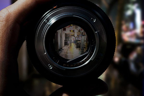 hand focusing camera lens with reflection of urban street scene in lens