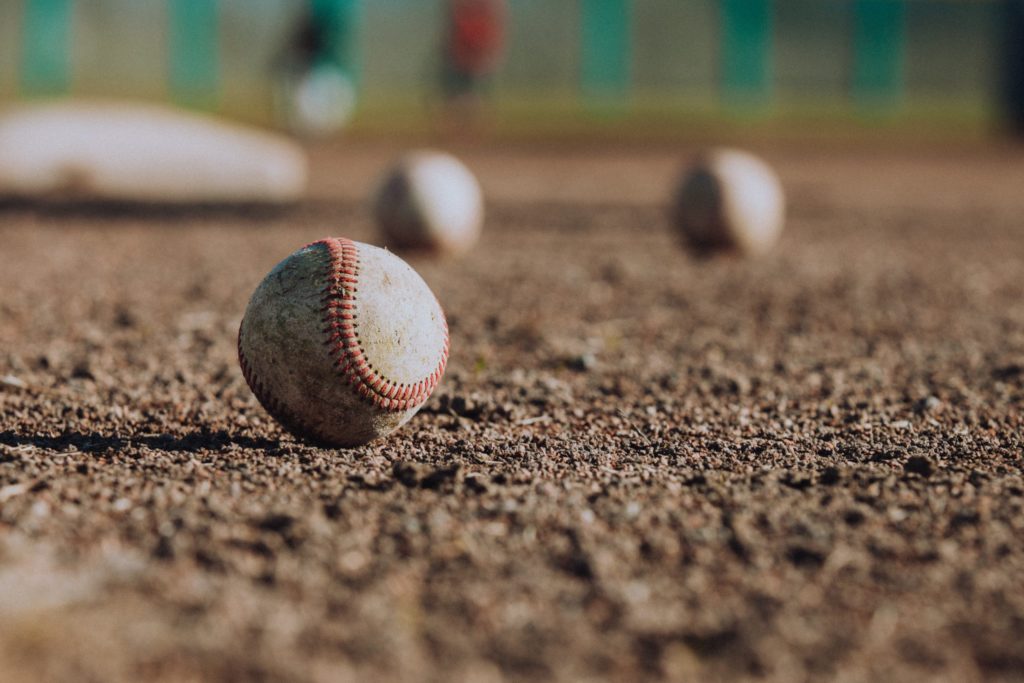 three baseballs on dirt with blurry blackgroun