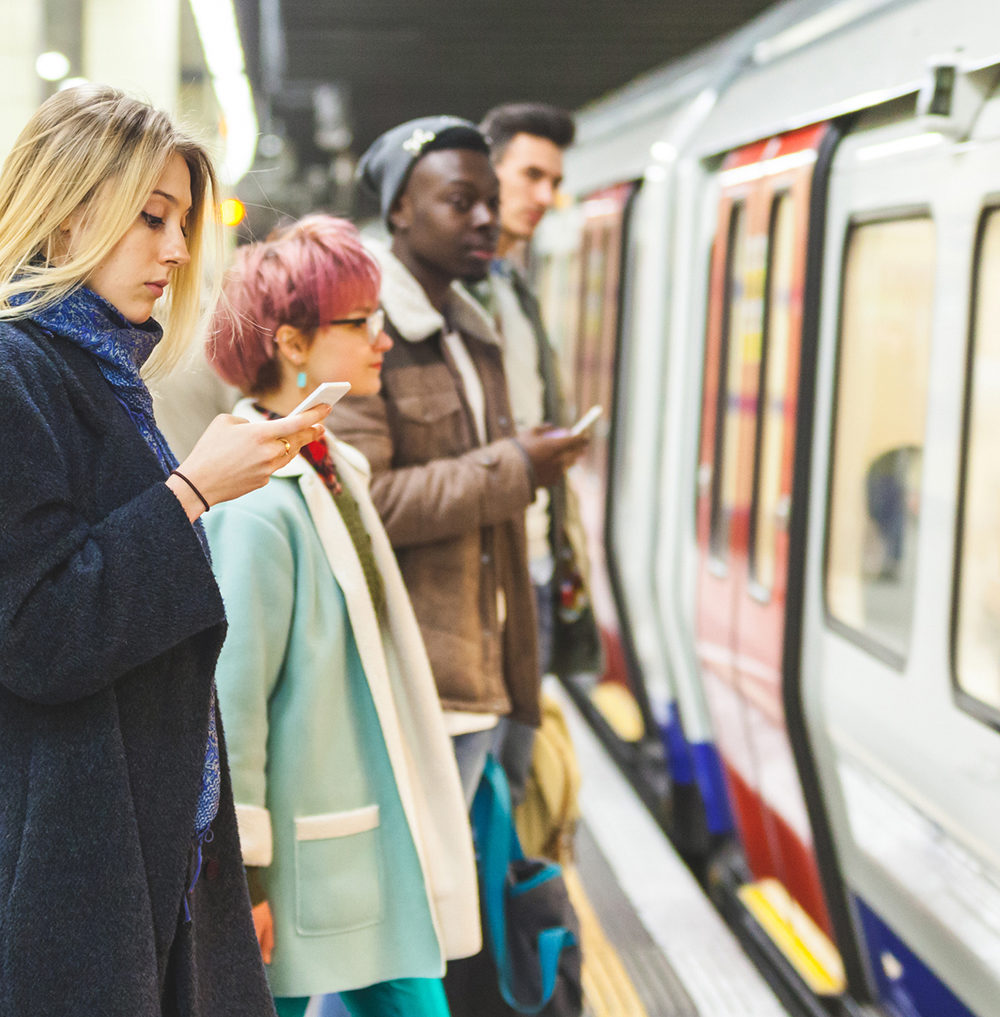 People waiting for the train at subway station. Mixed race persons, two men and two women, staying on a line and waiting to board the train. Commuting and transport